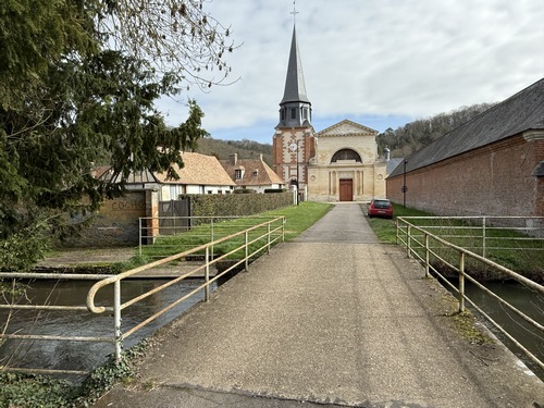 Regard arrière vers l'église en suivant la Promenade du Petit Pont qui franchit l'Iton.