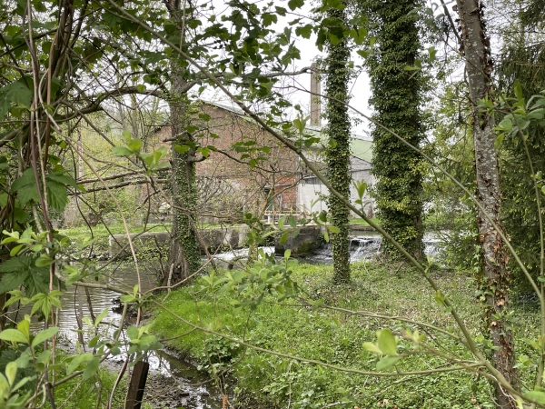 Derrière la végétation, l'ancien moulin devenu filature, puis fabrique de matelas.