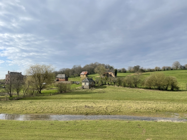 A notre gauche, les bâtiments dispersés d'une ferme sur la colline qui borde le Héron.