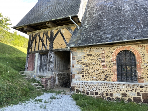 Le clocher domine un porche à pans de bois en sous-sol. Il faut descendre l'escalier, dont on voit l'ouverture devant nous, pour rejoindre le porche. Je vais suivre l'autre escalier, à gauche, pour contourner l'église.
