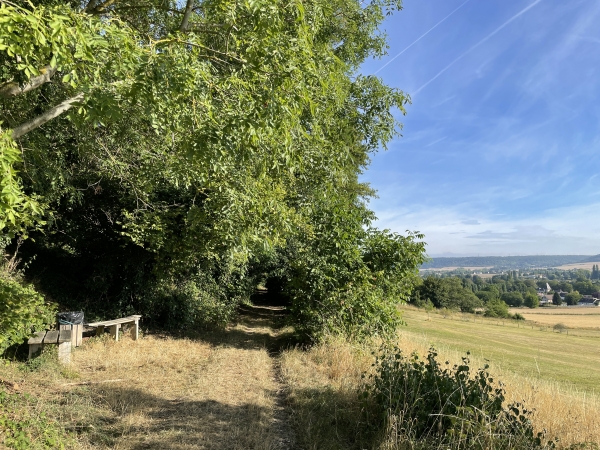 Bancs aménagés en bordure de chemin, avec panorama sur la vallée.