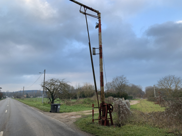 En traversant la N154, nous passons les vestiges du passage à niveau de l'ancienne voie ferrée Acquigny-Evreux. Dans l'attente d'une décision politique concernant l'avenir de cette ligne, elle a été réintégrée au réseau ferré national en 2011.
