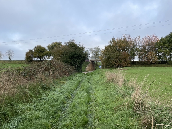Au bout du chemin, on peut deviner la présence de la véloloute au talus rectiligne et au pont de l'ancienne voie de chemin de fer de Dieppe à Fécamp, mise en service en 1880.