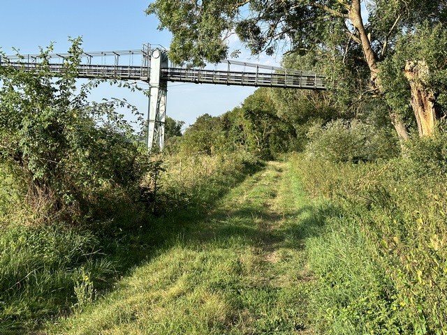 Le chemin passe sous la passerelle d'acheminement de granulats des carrières de Muids à Bernières-sur-Seine.