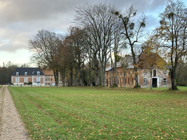 Derrière la grille, nous distinguons le château au loin. Nous allons suivre le chemin qui longe le parc.