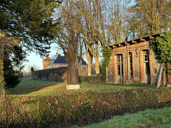 Un peu plus loin, derrière le saut-de-loup, nous devinons l'une des statues du parc dessiné par Le Nôtre en 1663. Dans le parc se trouvent sept statues en pierre ou marbre, un pont de pierre, les douves et les sauts-de-loup. En cette saison, les statues ont été recouvertes d'une toile de protection.