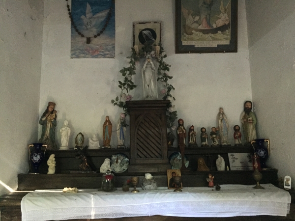 A l'intérieur de la chapelle : l'autel avec sa statuette de la Vierge, un tableau ex-voto et des dizaines de statuettes et plaques de reconnaissances.