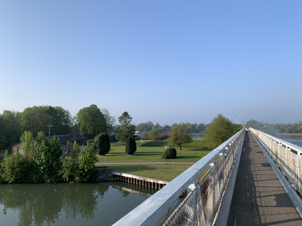 La passerelle vibre au-dessus des chutes d'eau du barrage de Poses. Une petite centrale hydro-électrique profite de la chute d'eau.