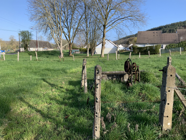 Avant d'arriver à la D23, et pour l'éviter, un sentier a été aménagé dans ce pré et le long des maisons. Le mécanisme du treuil est toujours à côté de son vieux puits, à droite.