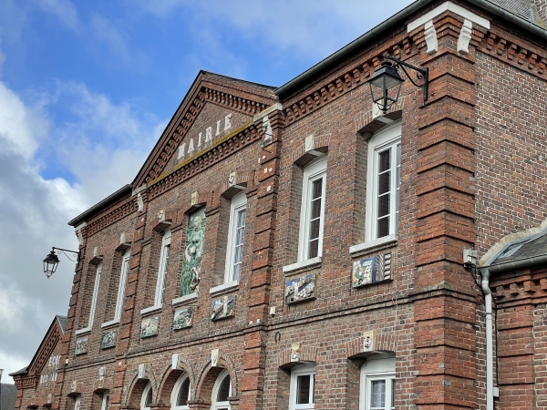 Les céramiques du fronton de la mairie de Nesle-Hodeng illustrent la fabrication du fromage de Neufchâtel.