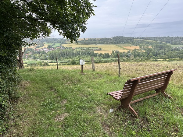 Un banc tourné vers la vallée a été installé à l'entrée d'Etocquigny. Le panneau, au milieu de la photo, est l'un des nombreux panneaux du Parcours de la Diversité qui présentent la flore locale.