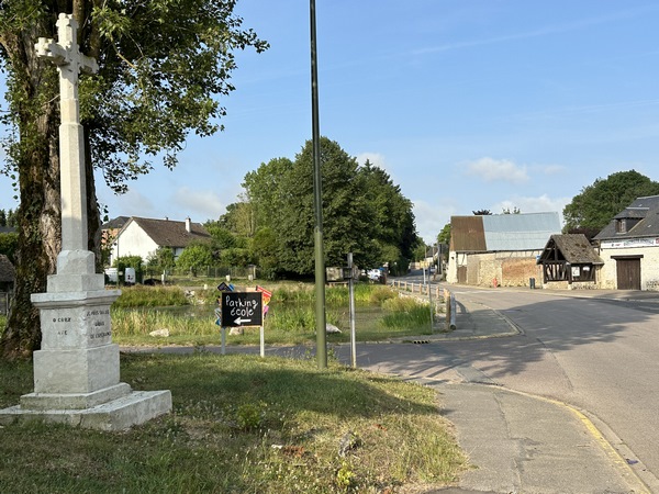 Dans Vraiville, nous laissons la D81, et tournons ici à gauche, entre le calvaire et la mare.