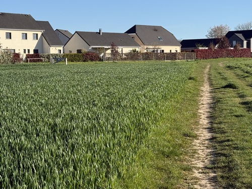 Le prochain chemin se trouve à gauche, avant les premières maisons de Boos. On distingue la barrière de bois de l'entrée du chemin.